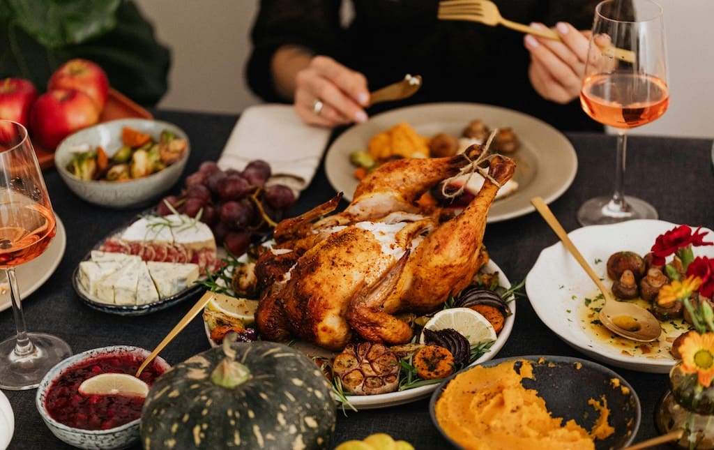 Turkey dinner spread with rose and hands of woman eating