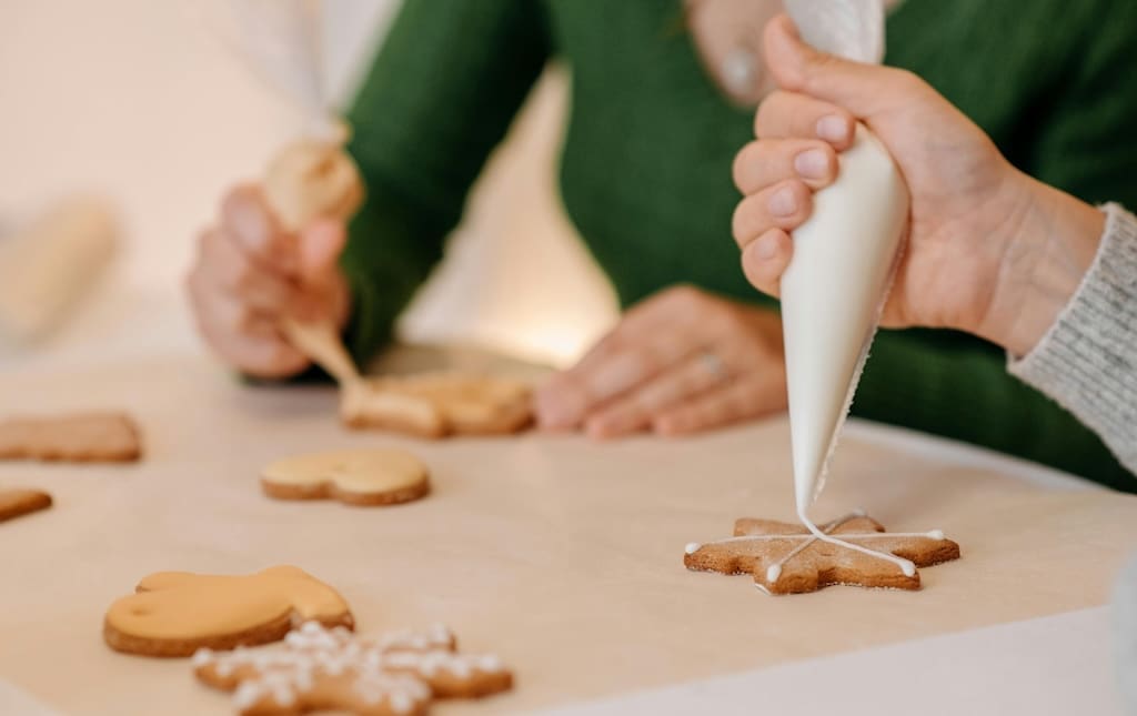 Close up of hand decorating a snowflake cookie