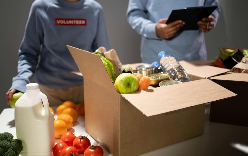 Box of food on table with volunteers in the background