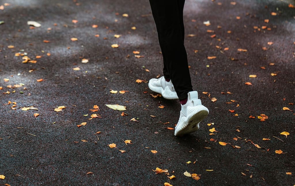 Legs of woman running with fall leaves scattered on the ground