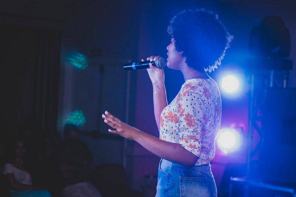 A Black woman singing into a microphone woman singing on stage