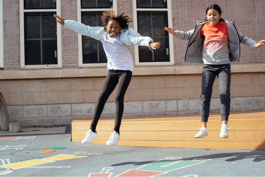 A Black and Latina girl jumping kids playing hop scotch