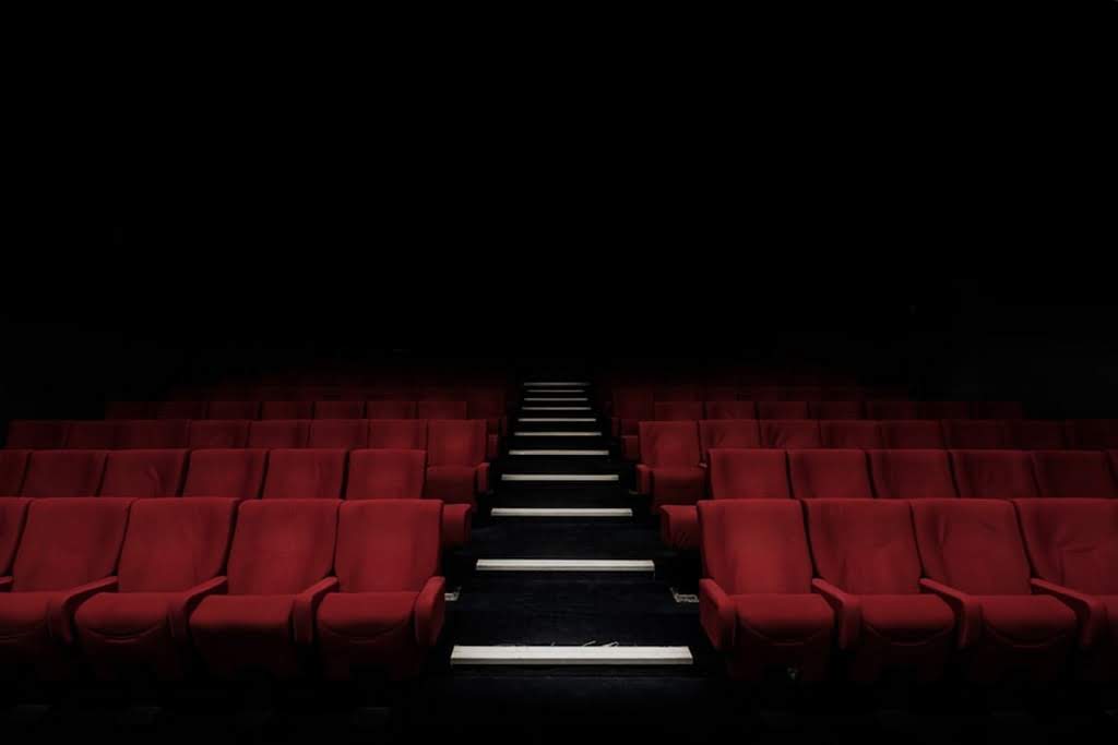 A dark, empty movie theater with red seats empty movie theatre