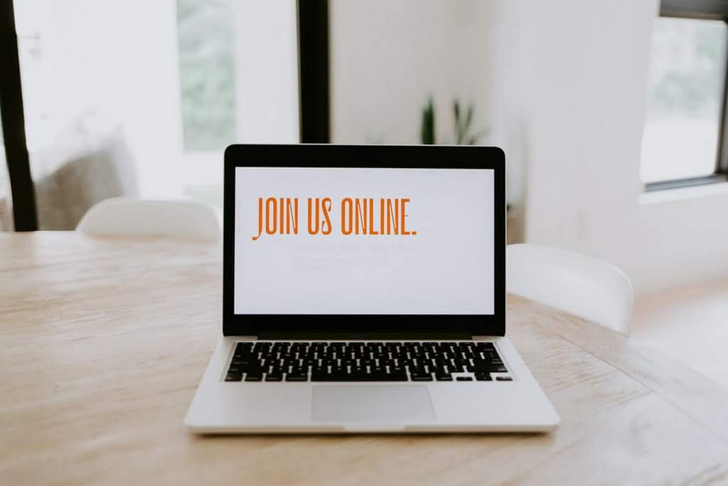 A laptop with the phrase "Join Us Online" on the screen join us online banner on a laptop