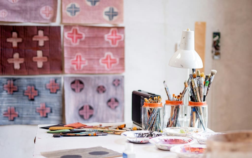 Art supplies and hand-painted cloth in the background