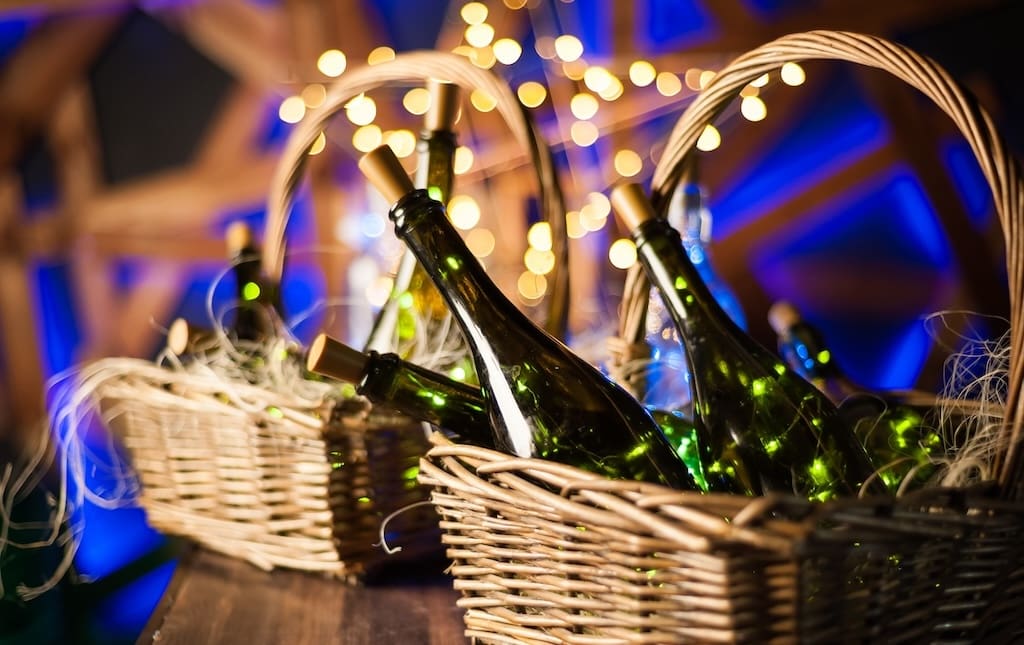 champagne bottle set with Christmas basket, gold garlands on dark brown wooden background, new year celebration concept