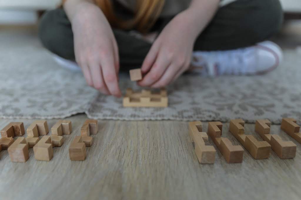 Two hands playing with puzzles on the floor jenga style blocks