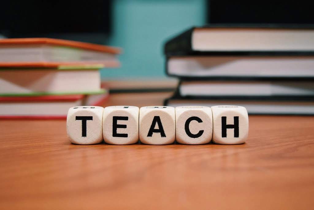 A set of dice with letters spelling the word "TEACH" letter dice
