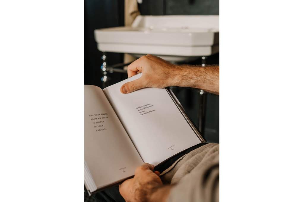 A pair of hands holding up a book of poetry man reading book