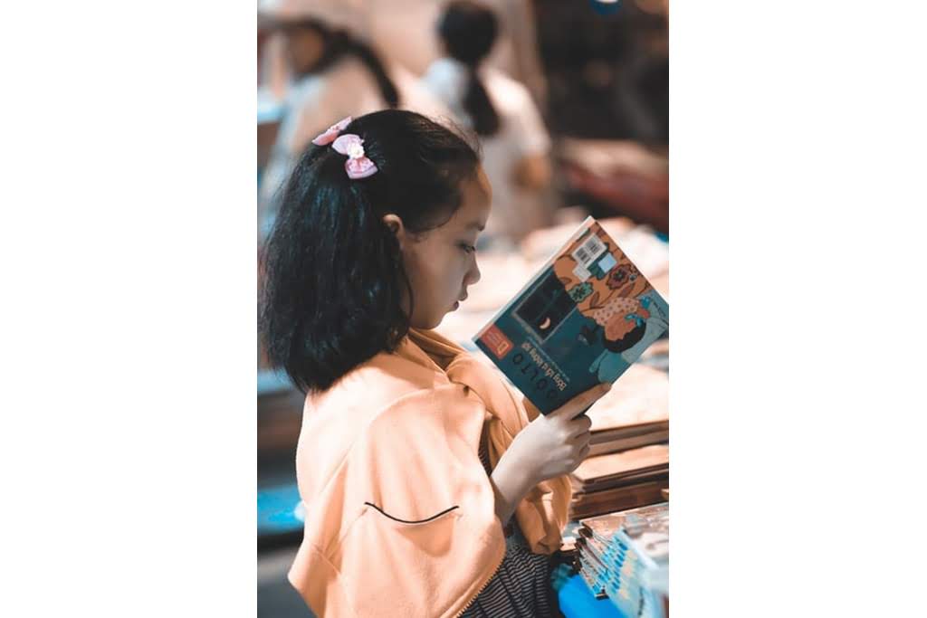 An Asian girl reading a book girl reading at table