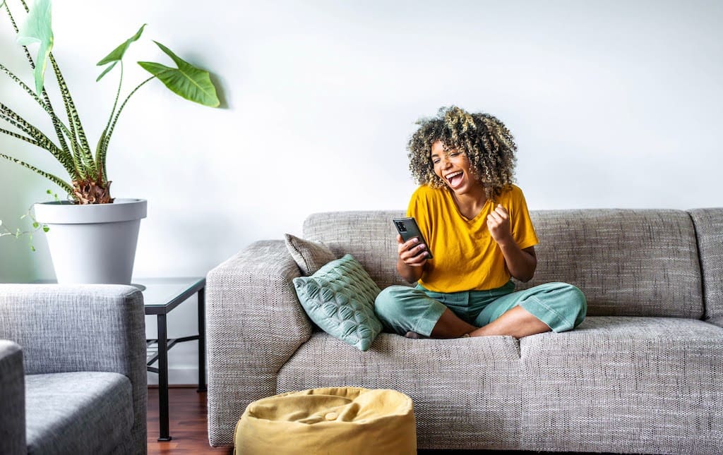 Woman Sitting On the Couch Making Phone Calls Smiling