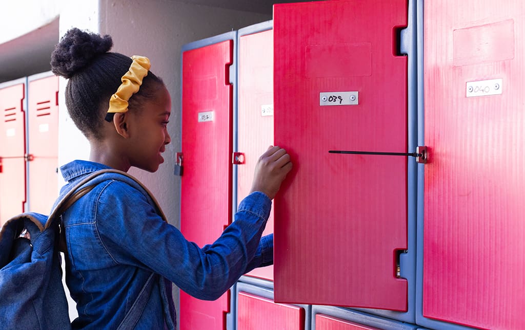 A student stands in front of a pink locker
