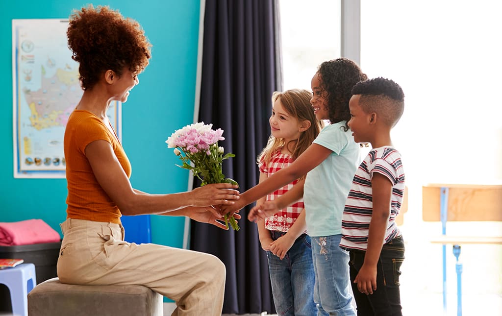 Students give a teacher flowers on Teacher Appreciation Day