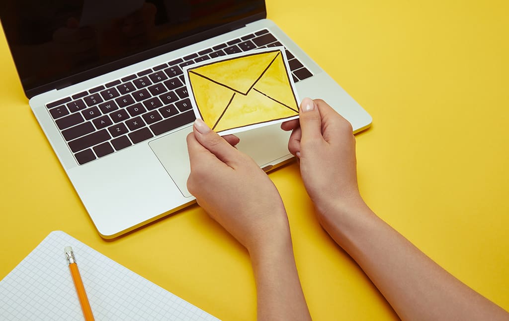 Concept of hands holding an email message in front of a laptop