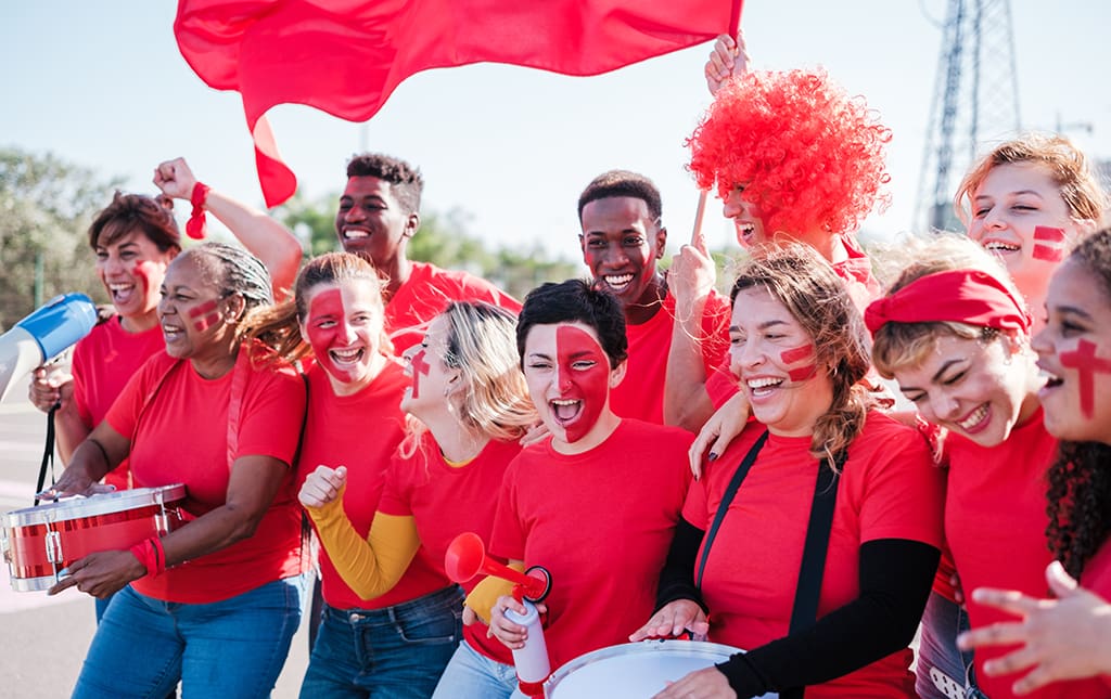 Alumni wearing team colors cheer on a high school soccer team.