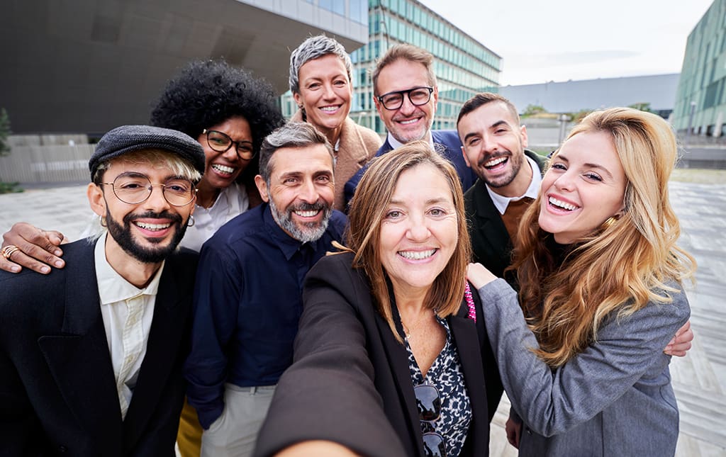 A group of alumni snap a quick selfie outside a school